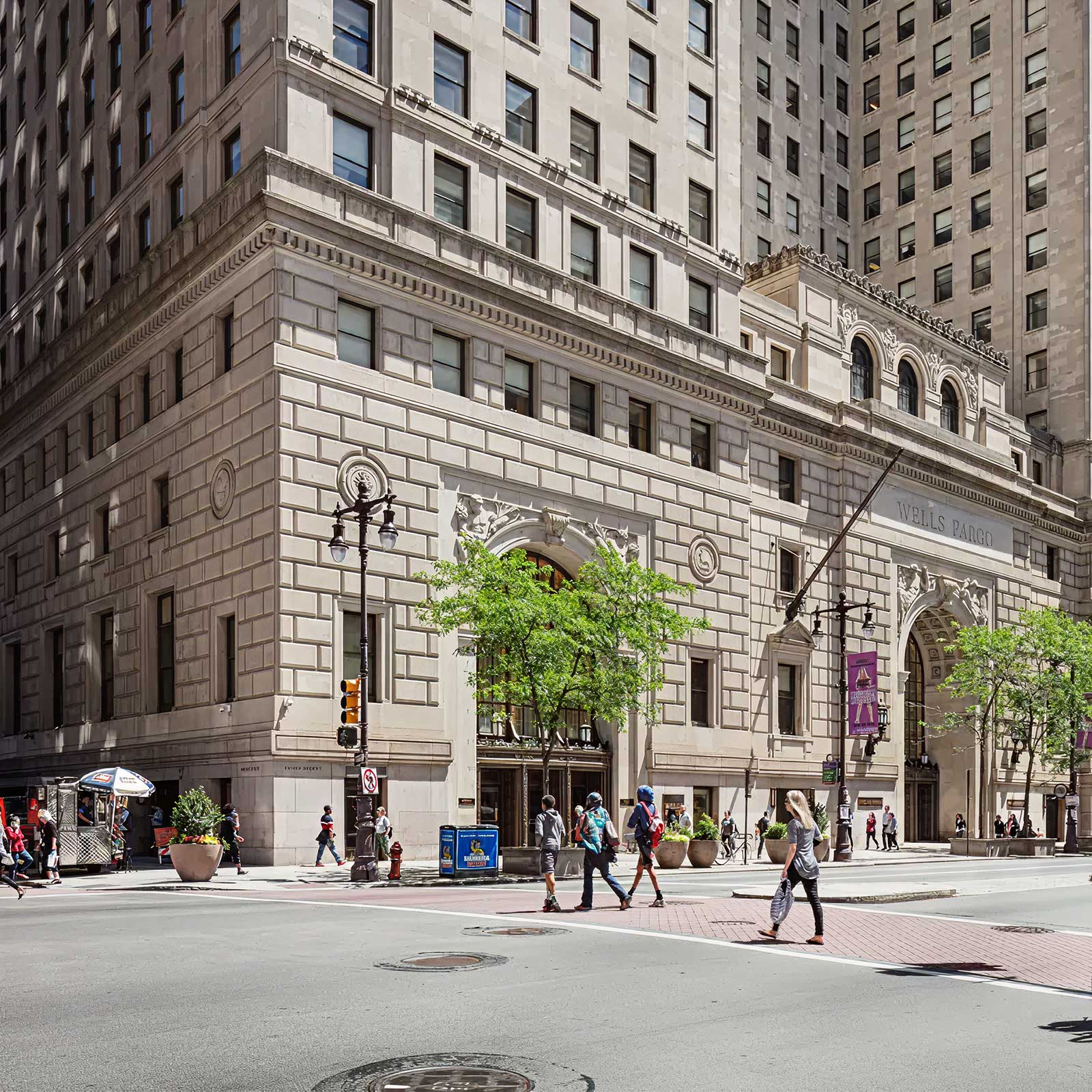 Historic downtown office building with ornate architectural details, street-level pedestrians, and surrounding high-rise buildings in an urban business district.