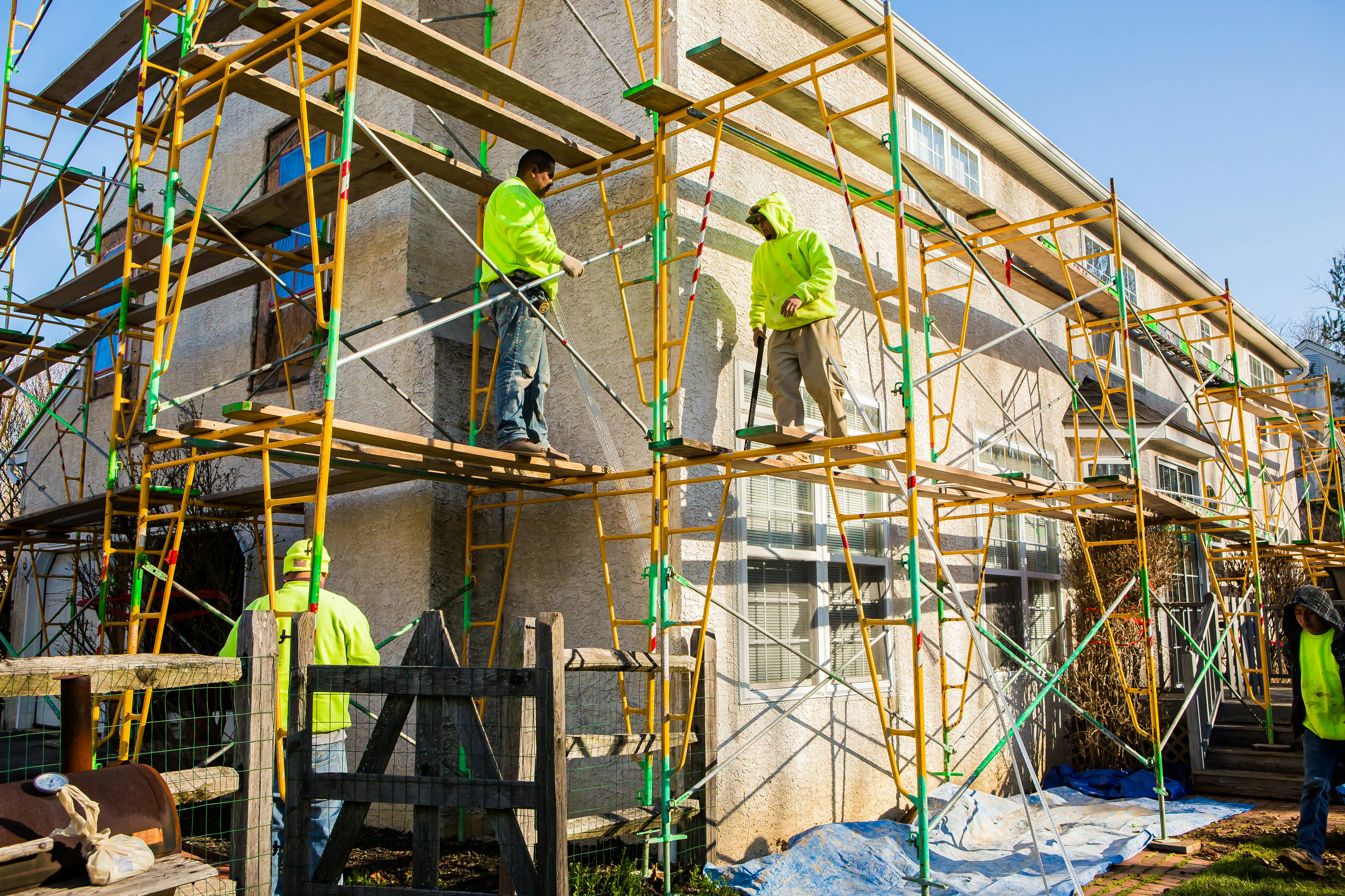 workers on scaffolding on house