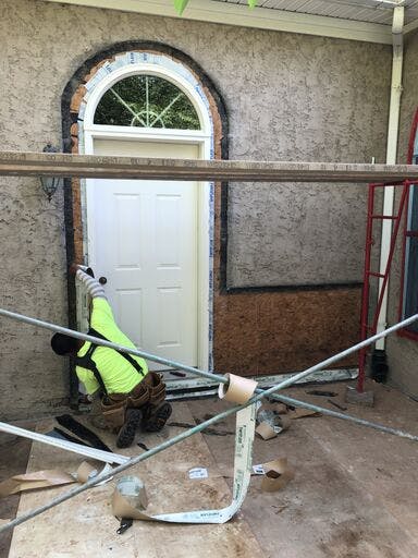 white suburban house with in progress stucco remediation