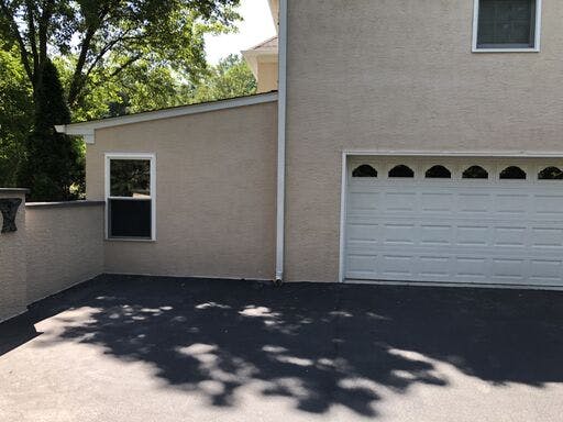 garage of white suburban house with in progress stucco remediation