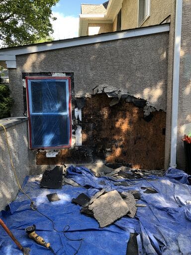 garage of white suburban house with in progress stucco remediation