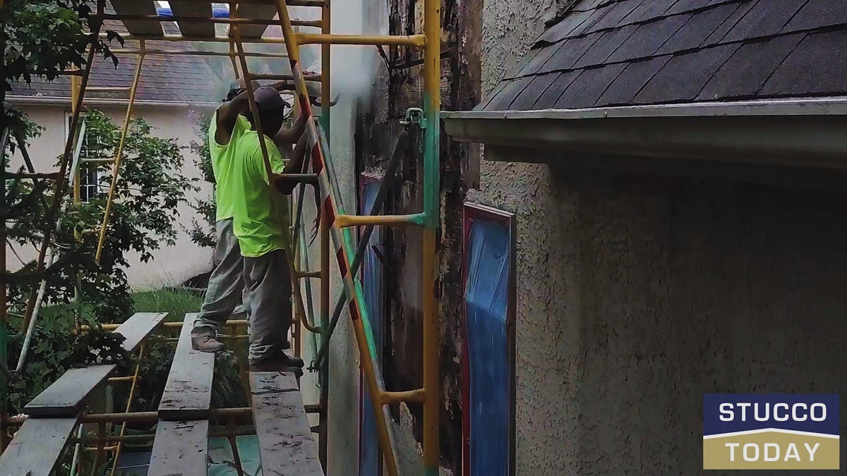 two guys working on stucco remediation for a large house in wester chester, pa