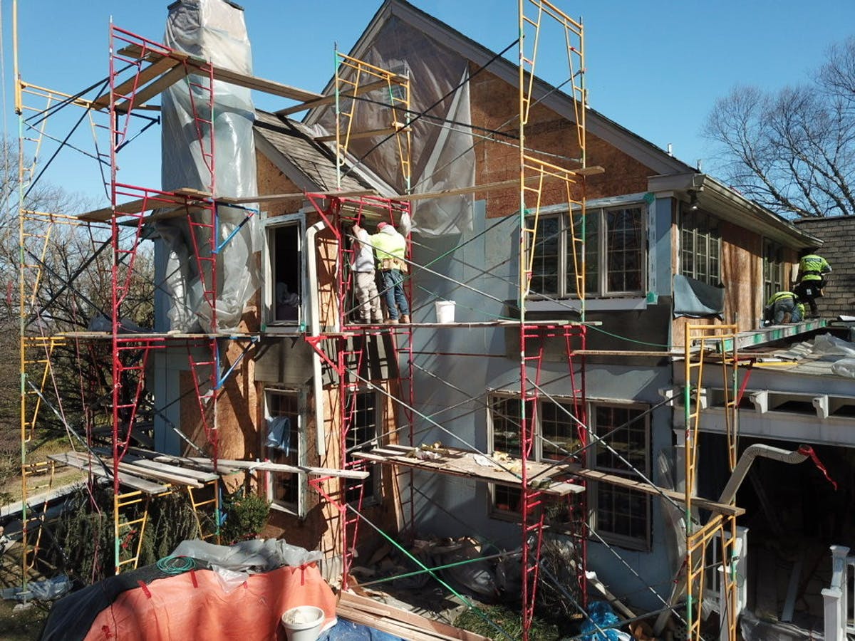 white suburban house with in progress stucco remediation